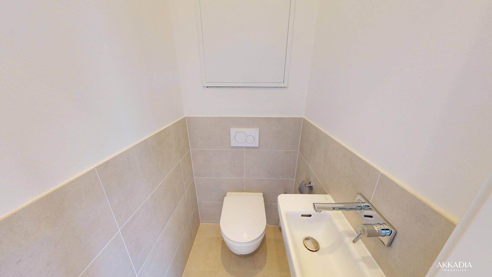 Kleines, modernes Gäste-WC mit Wand-WC, Handwaschbecken und hellen Fliesen.