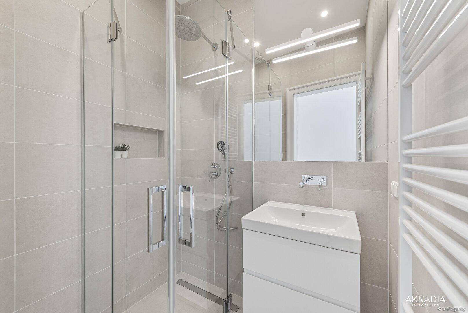 Modernes Badezimmer mit begehbarer Dusche, Waschtisch und beheiztem Handtuchhalter.
