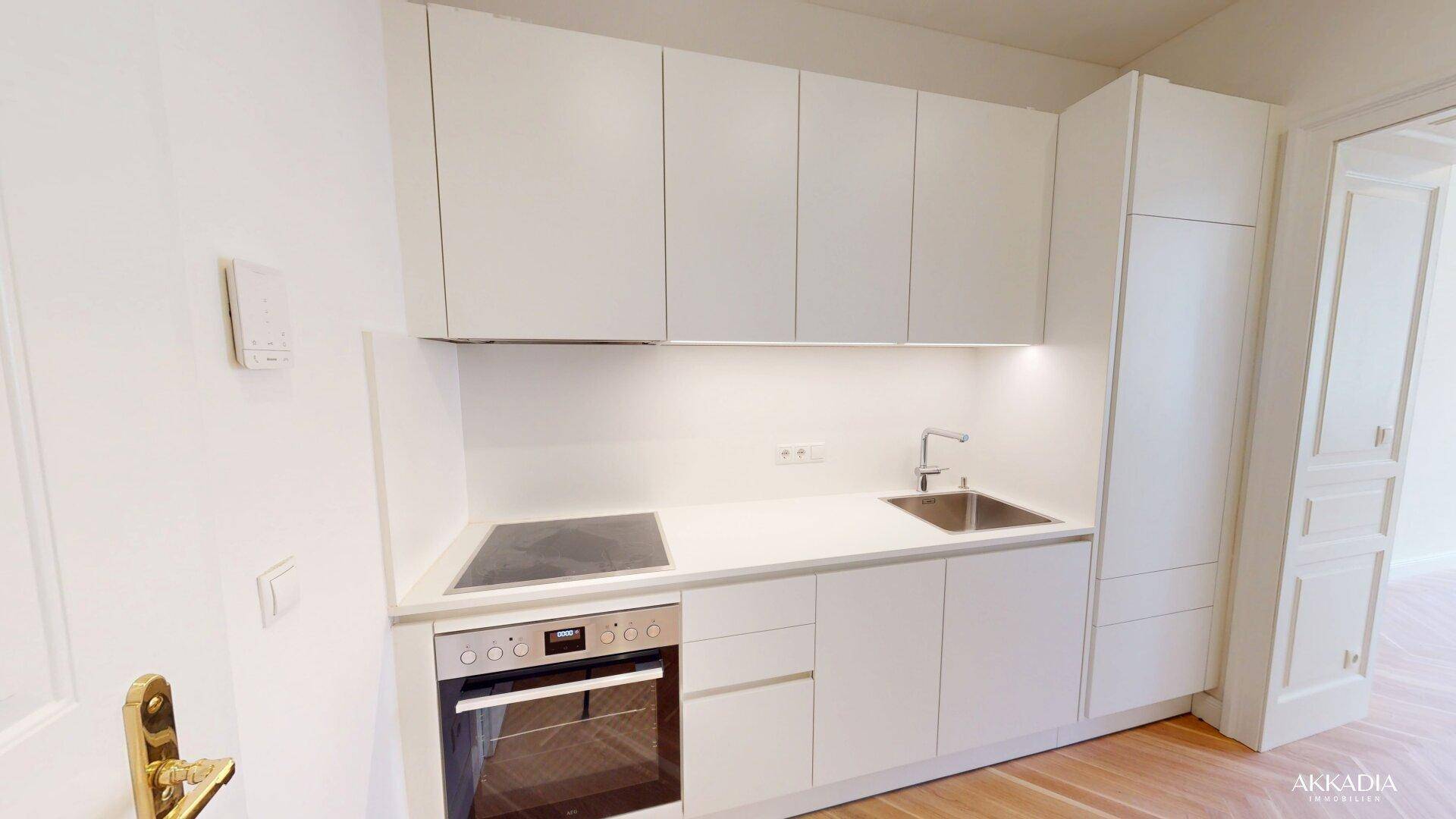 Moderne weiße Küchenzeile mit integriertem Induktionskochfeld und Backofen in minimalistischem Design.