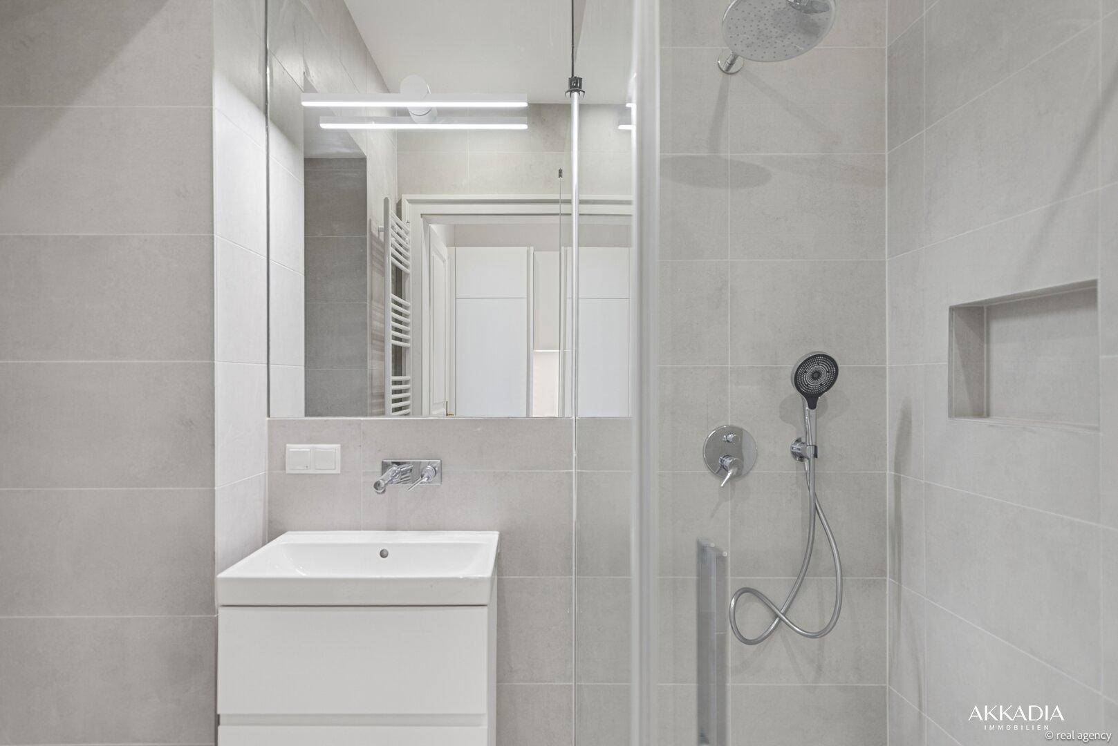 Detailansicht des modernen Badezimmers mit Waschtisch, Spiegel und begehbarer Dusche.