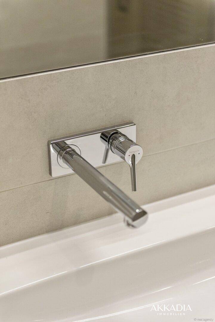 Elegante Wandarmatur über einem modernen Waschbecken in einem stilvollen Badezimmer.