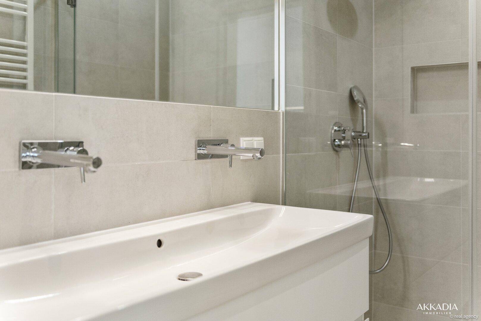Modernes Badezimmer mit großformatigen Fliesen, Einzelwaschbecken und Duschbereich.