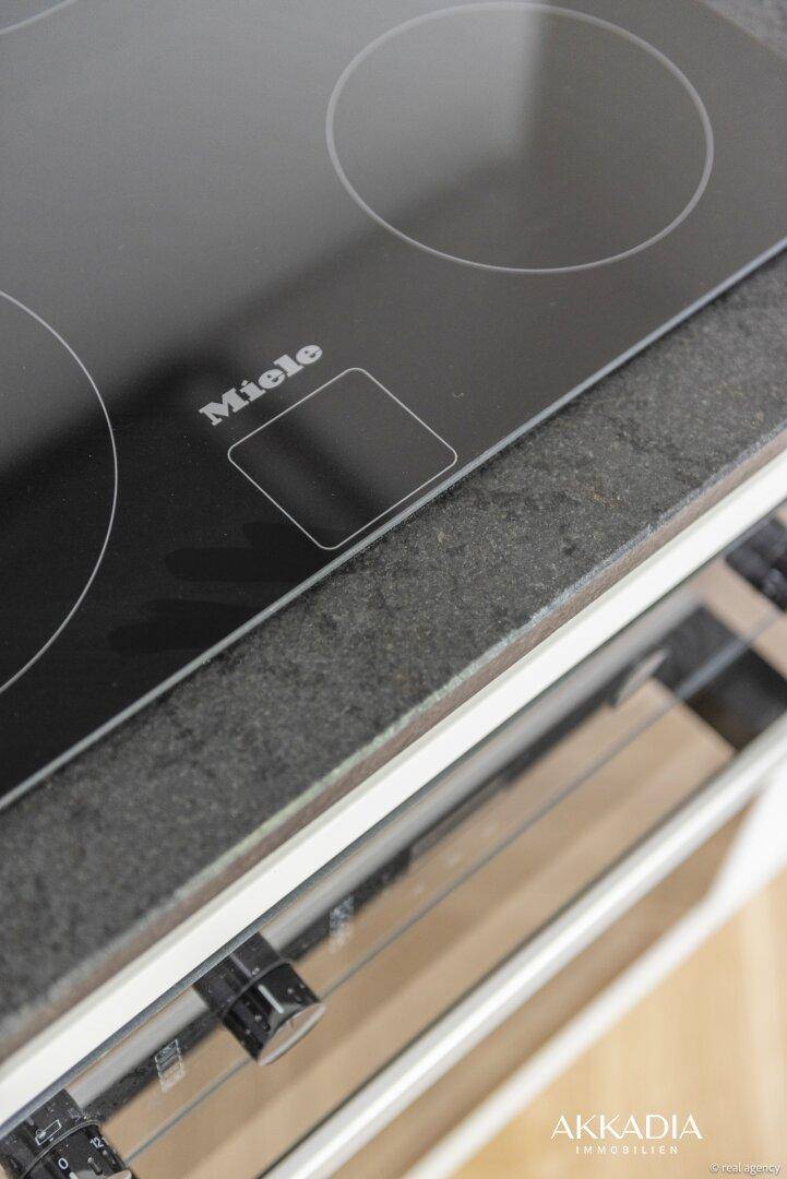 Detailansicht eines modernen Miele Induktionskochfeldes auf einer dunklen Arbeitsplatte in der Küche.
