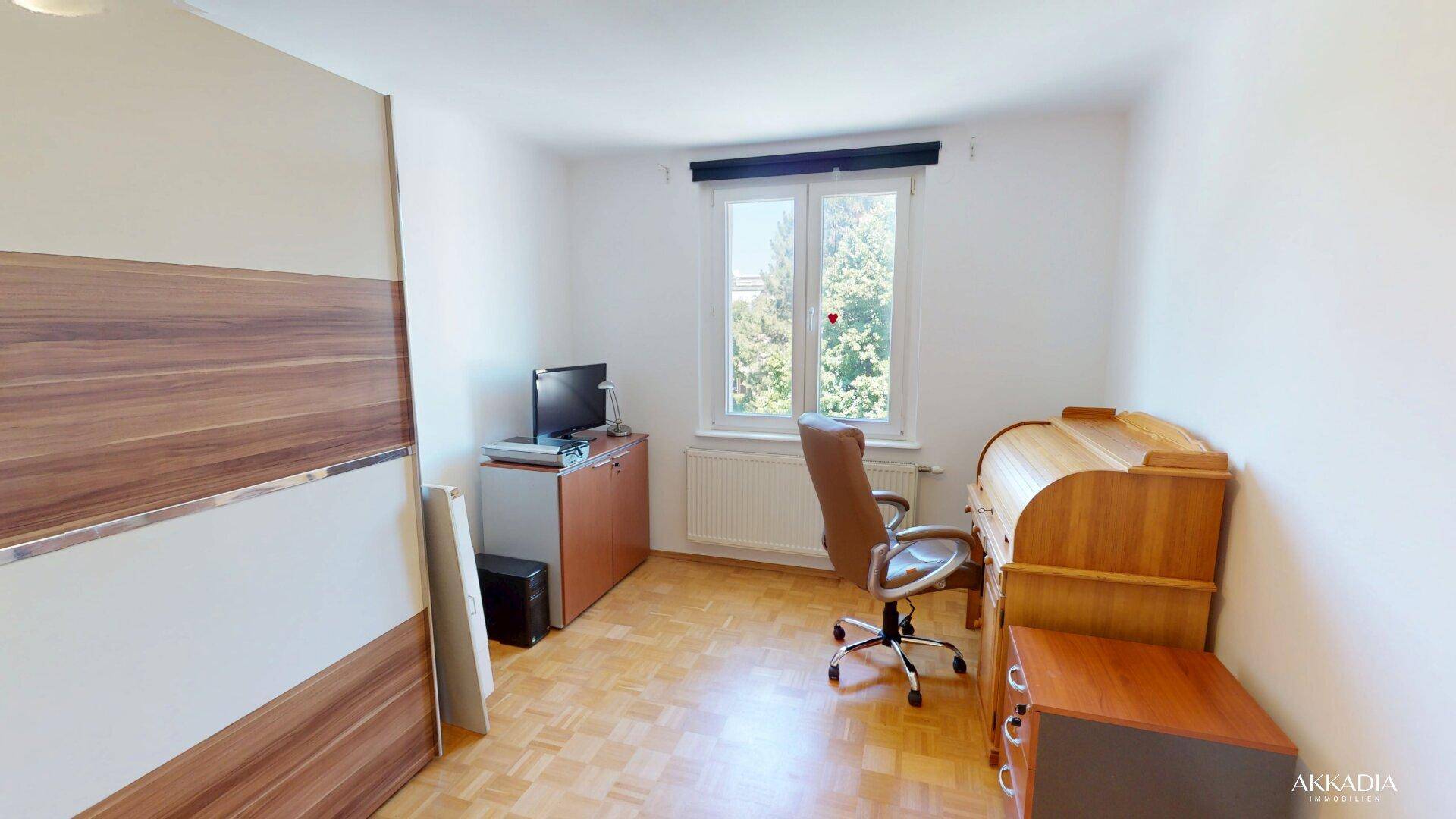 Arbeitszimmer mit Schreibtisch, Bürostuhl und Holzmöbeln, bietet einen angenehmen Blick ins Grüne.