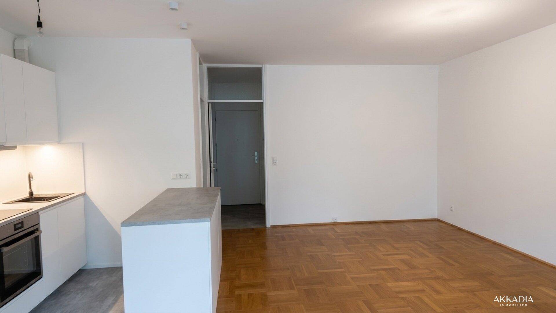Offener Wohnbereich mit Parkettboden und Zugang zu weiteren Räumen.