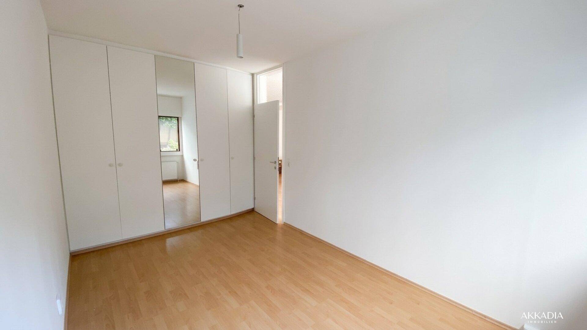 Schlafzimmer mit integrierten weißen Kleiderschränken und Laminatboden.