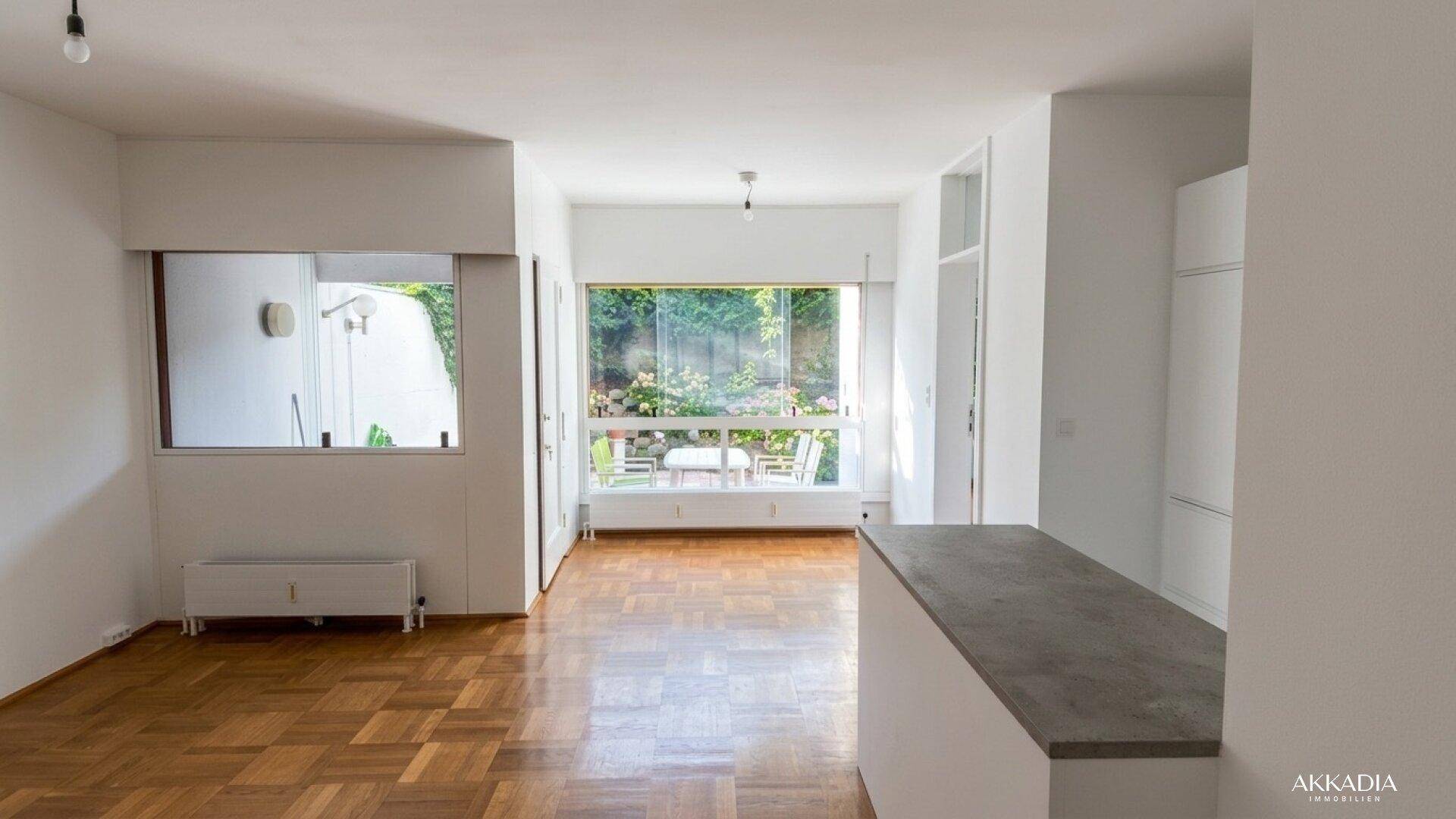 Geräumiger Wohnbereich mit Parkettboden, offener Küche und Blick in den Garten.