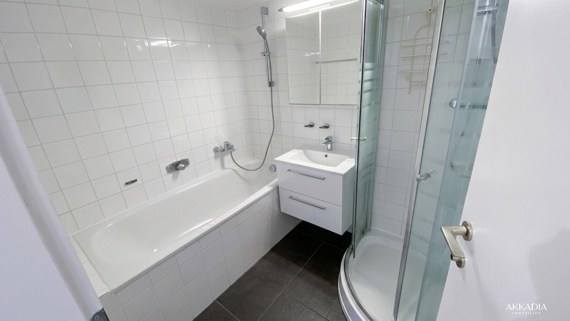 Modernes Badezimmer mit Badewanne, Duschkabine und weißen Fliesen.