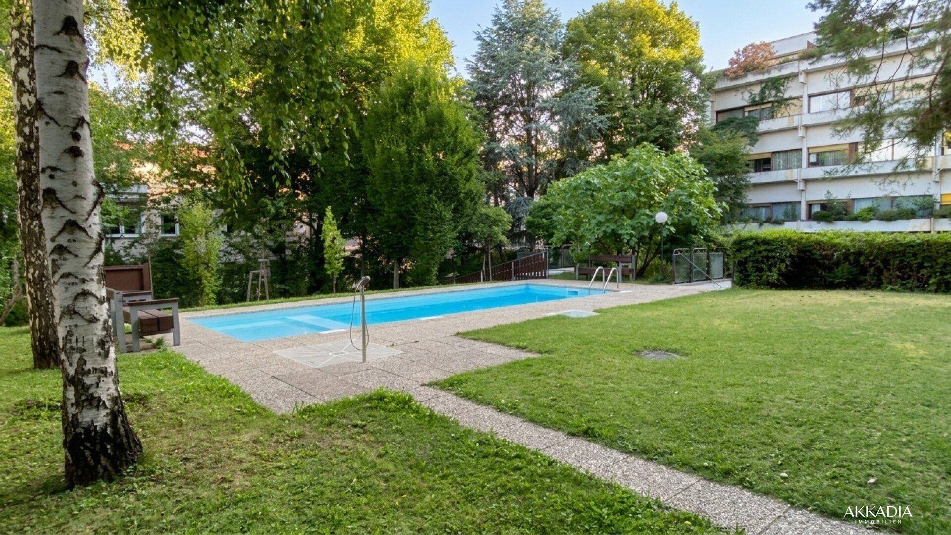 Gemeinschaftlicher Außenbereich mit Swimmingpool, Liegewiese und altem Baumbestand.