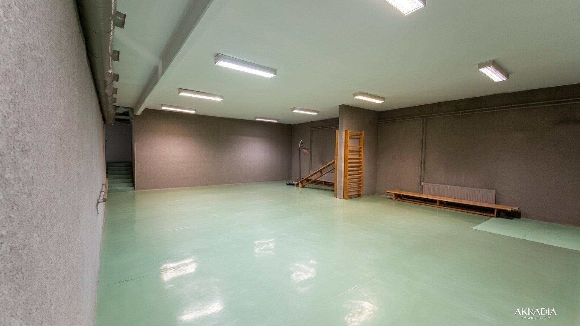 Großer Fitnessraum im Untergeschoss mit Sportgeräten und viel Platz für Training.