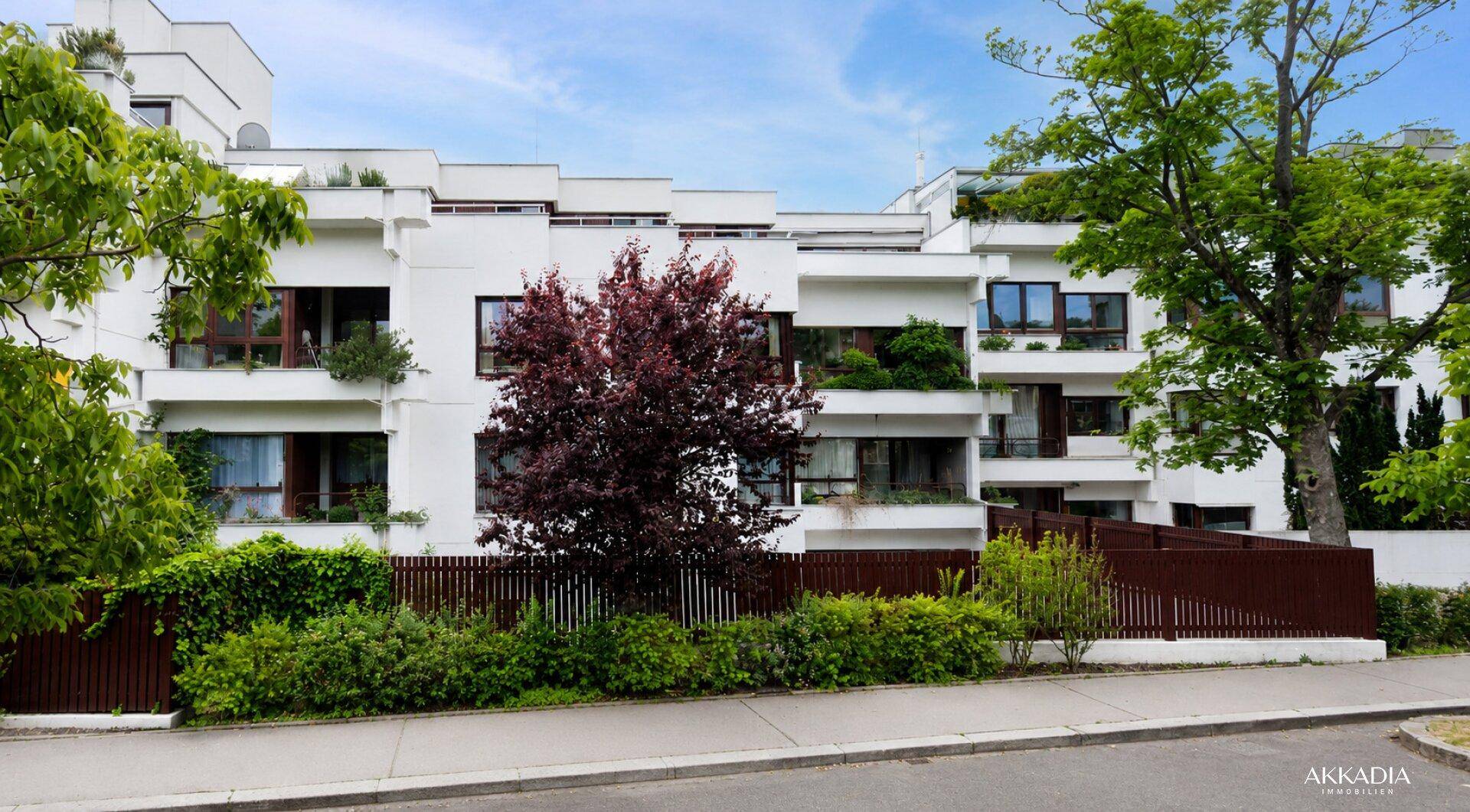 Moderne Wohnanlage mit weißer Fassade, großen Fenstern und Balkonen.