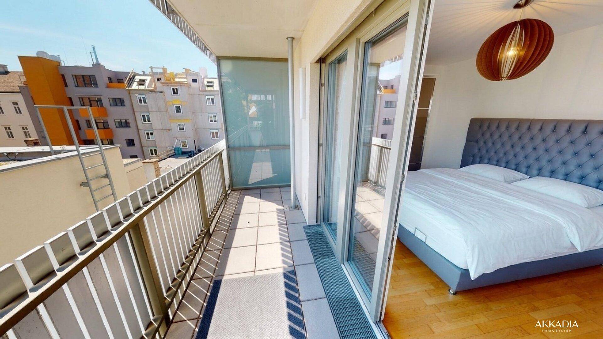 Schlafzimmer mit großem Bett und direktem Zugang zu einem sonnigen Balkon mit Stadtblick.