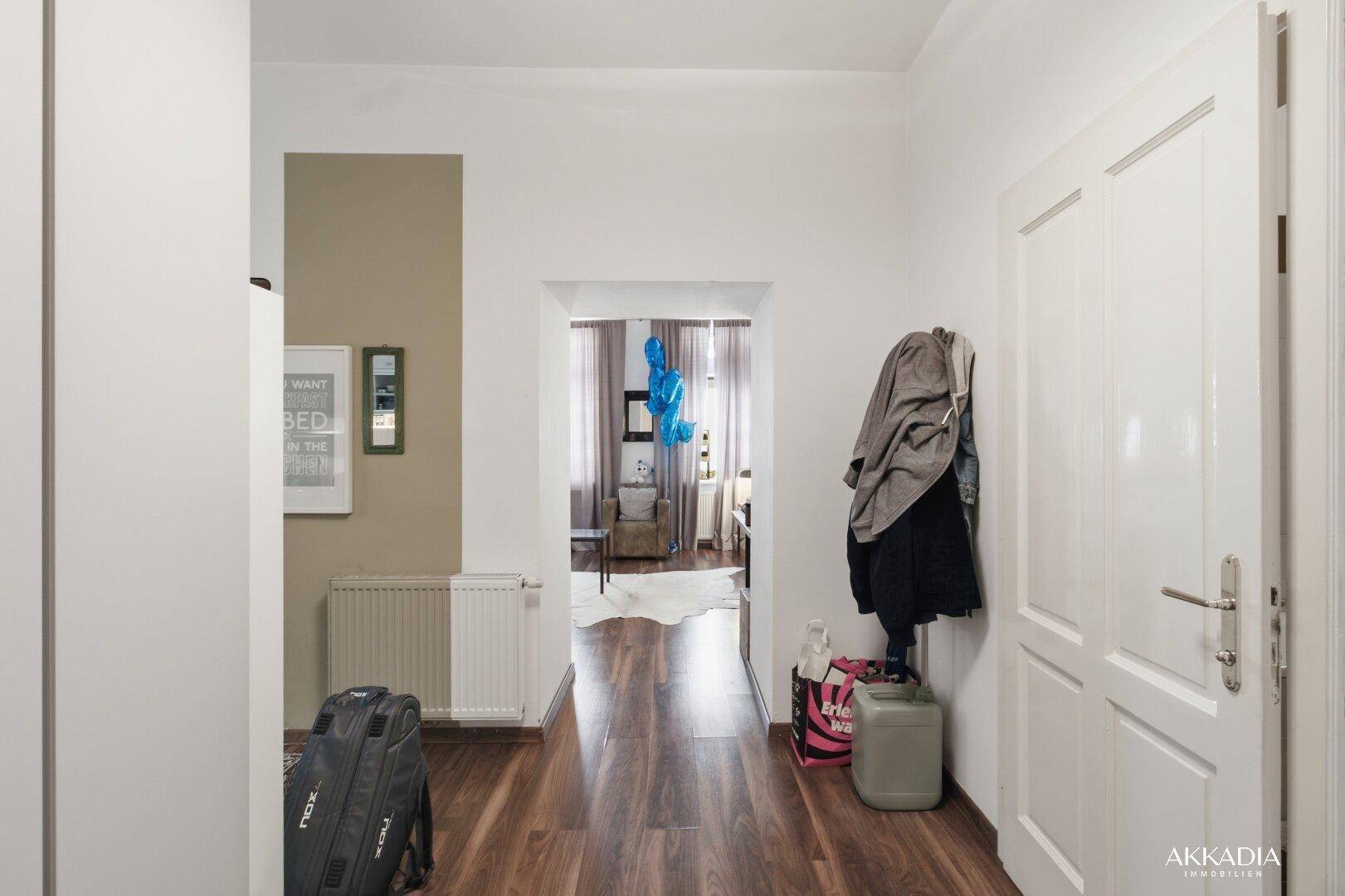 Eingangsbereich mit Holzboden, Garderobe und Blick in den Hauptwohnbereich.