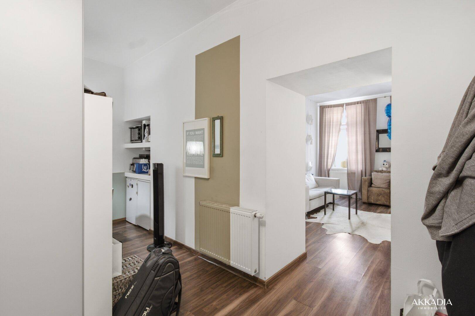 Heller Flur mit Holzboden und Blick in den Wohnbereich der Wohnung.