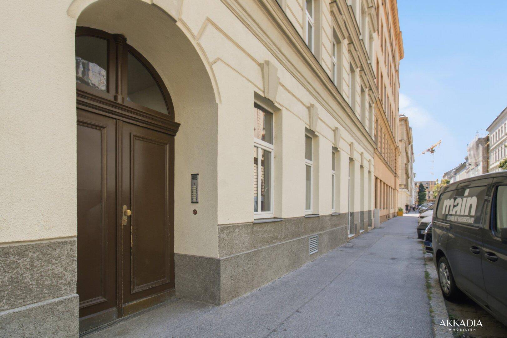 Historische Fassade des Gebäudes mit großem Holztor und gepflastertem Gehweg.