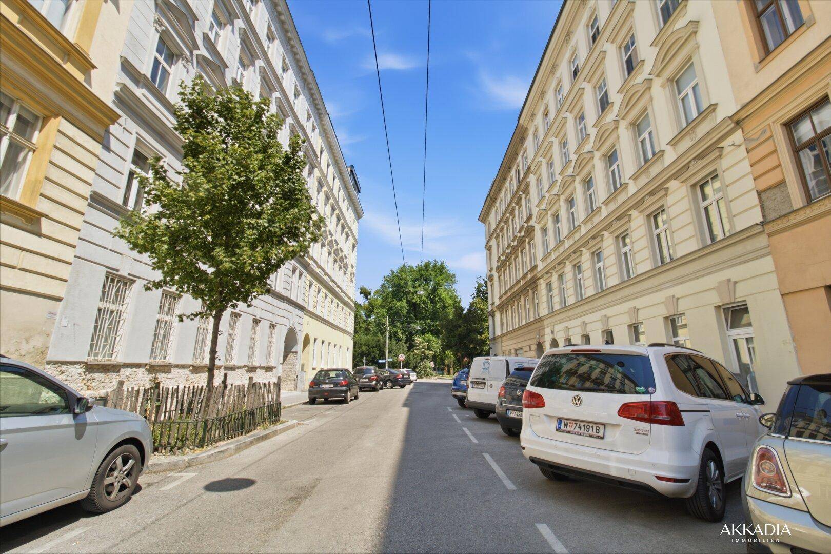 Ruhige Wohnstraße mit historischen Gebäuden, Bäumen und geparkten Autos.