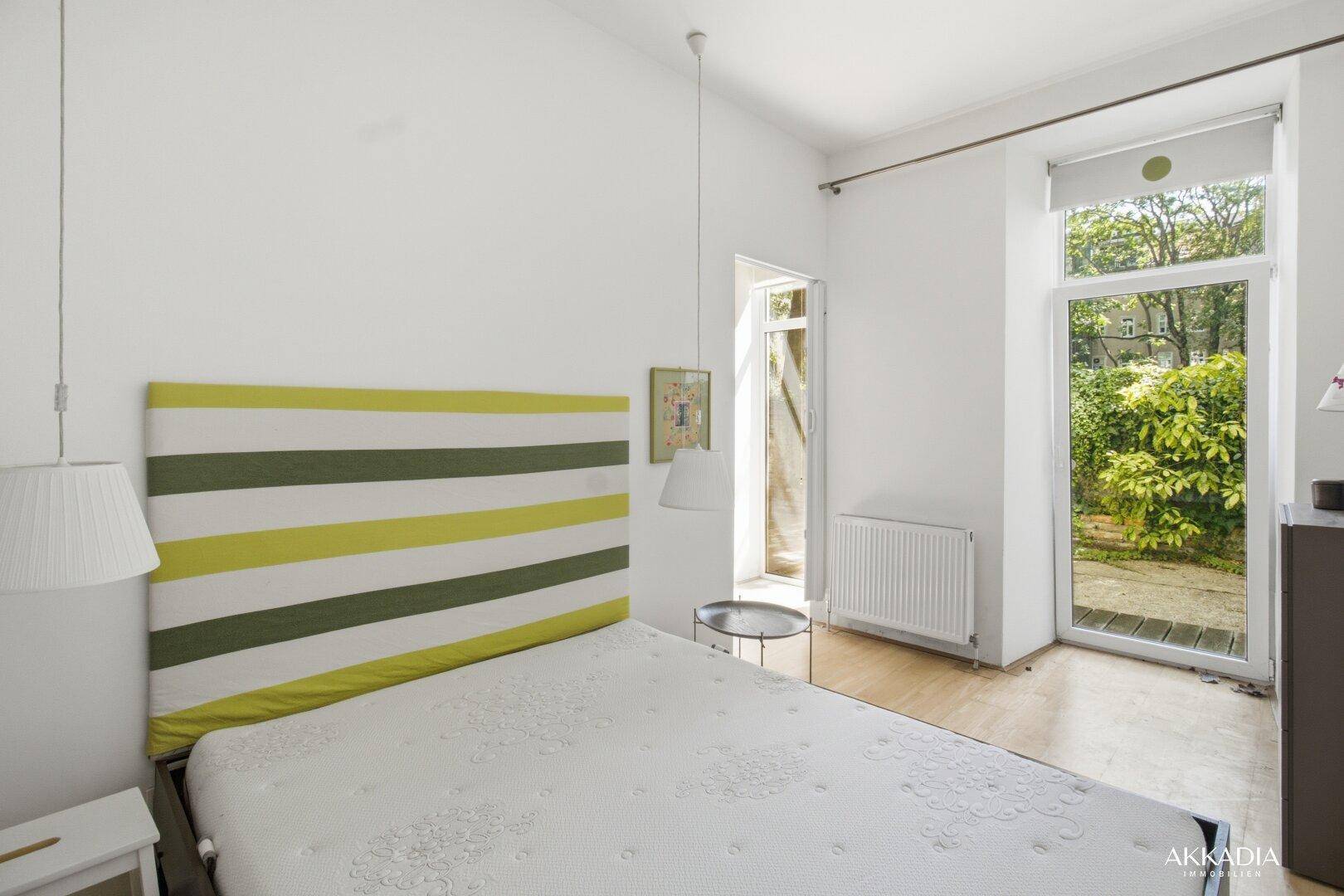 Schlafzimmer mit Bett, Heizkörper und direktem Zugang zu einem privaten Außenbereich.