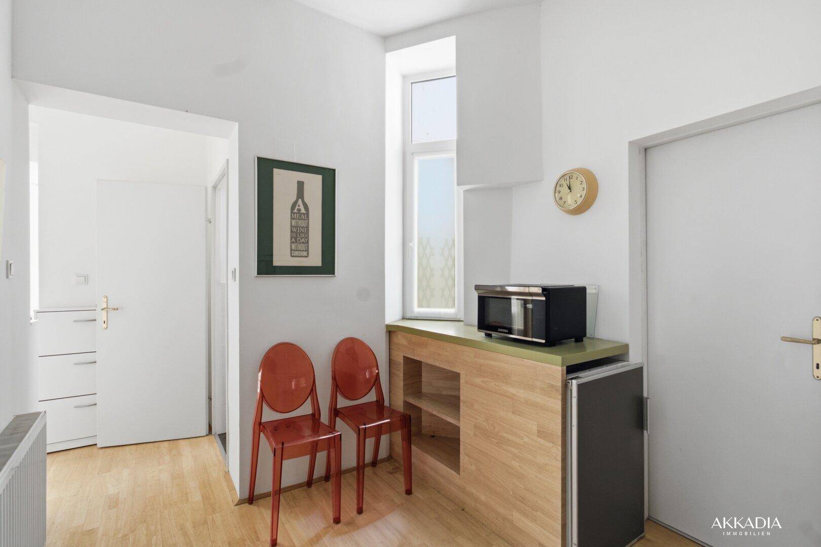 Kleine Küchenzeile mit Mikrowelle, Arbeitsfläche und Fenster für Tageslicht.