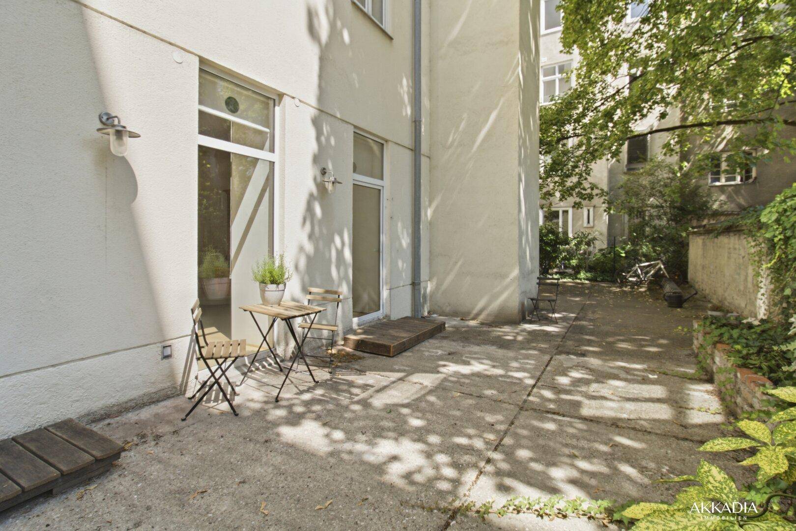 Außenbereich mit kleiner Terrasse und Zugang zu den Innenräumen, umgeben von viel Grün.