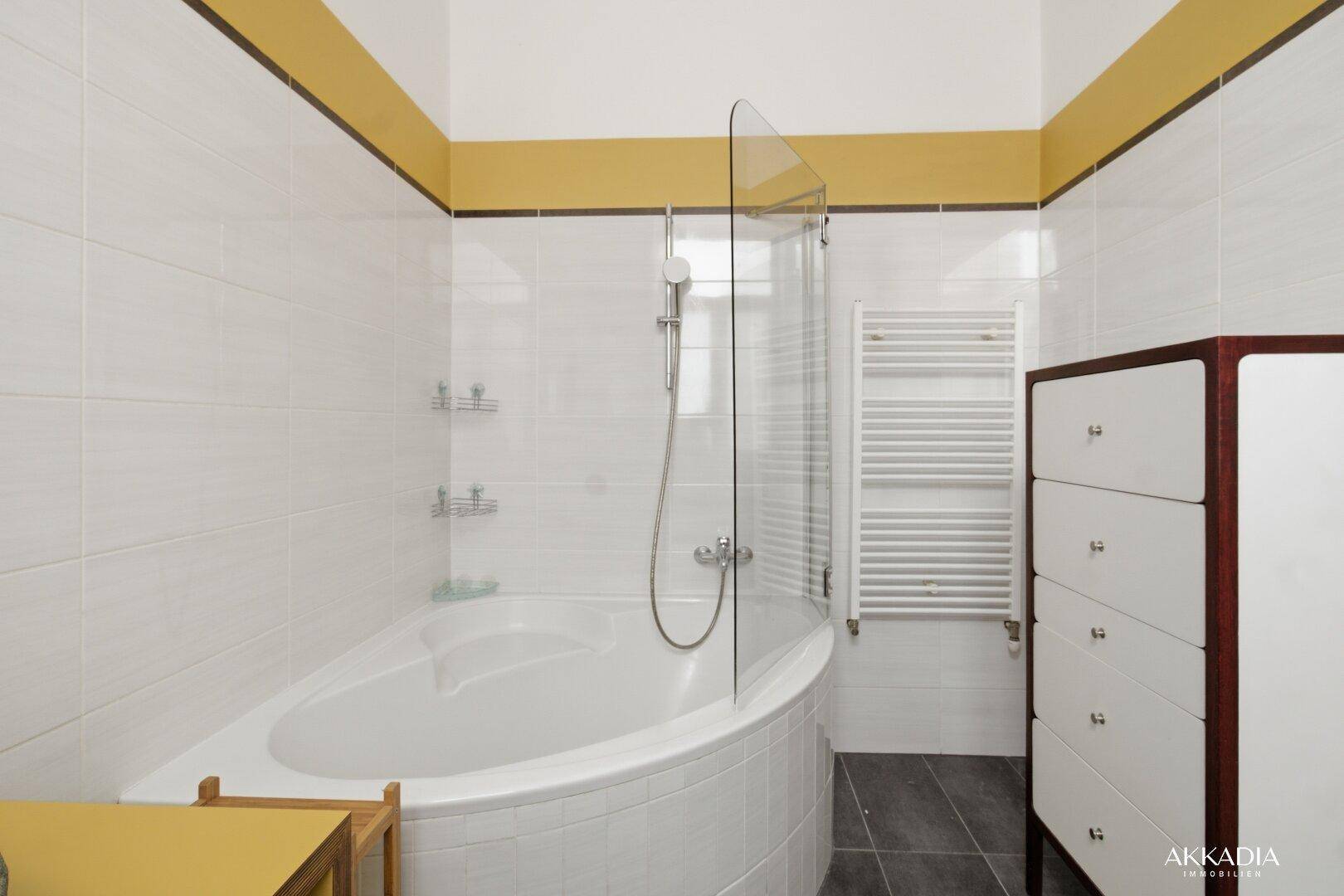 Badezimmer mit Eckbadewanne, Duschabtrennung und praktischem Handtuchheizkörper.