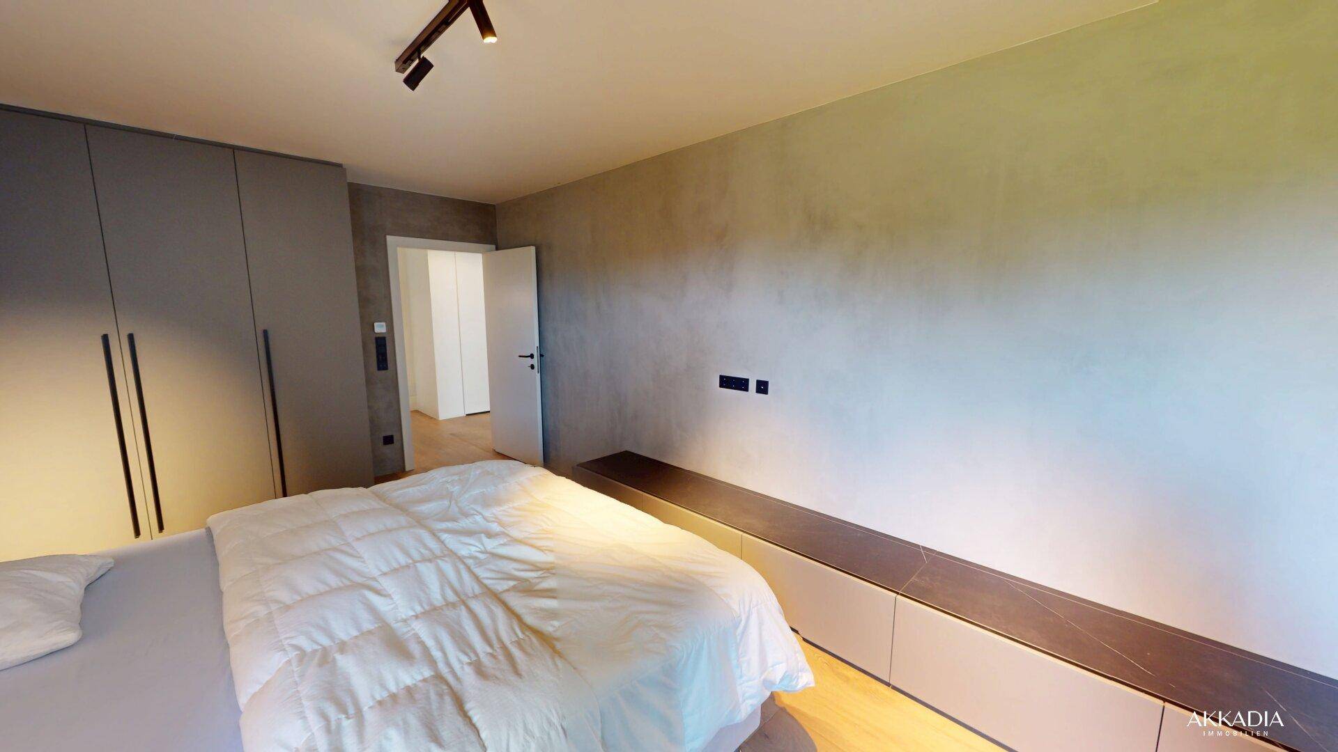 Geräumiges Schlafzimmer mit integrierten Kleiderschränken, Holzboden und minimalistischer Einrichtung.