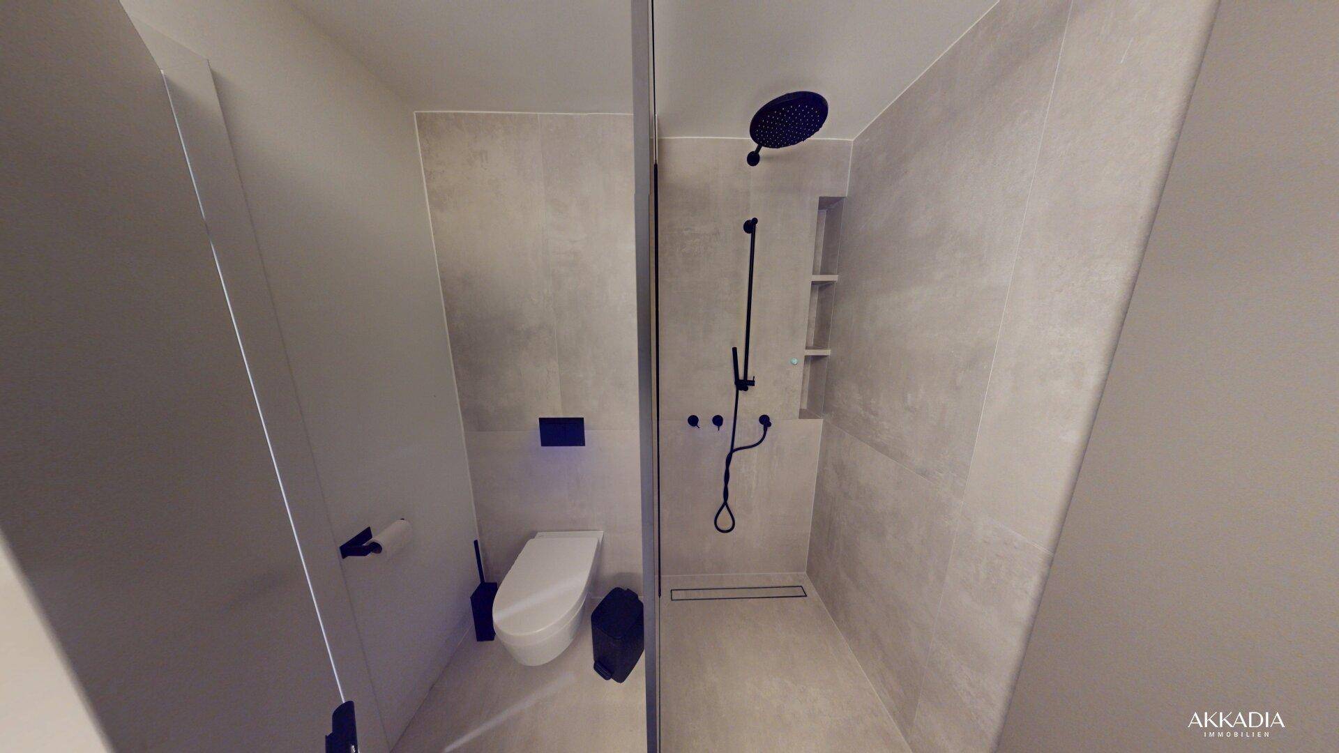Modernes Badezimmer mit begehbarer Dusche, schwarzen Armaturen und wandhängendem WC, komplett gefliest.