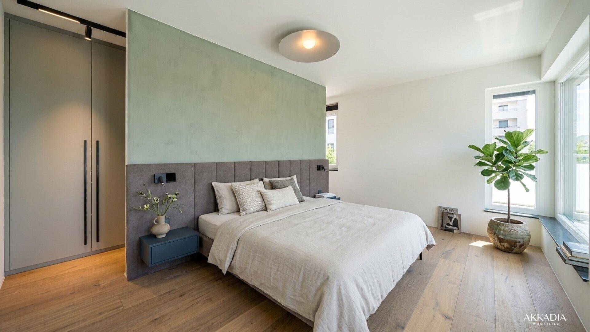 Geräumiges Schlafzimmer mit grüner Akzentwand, Einbauschränken und großen Fenstern für viel Licht.
