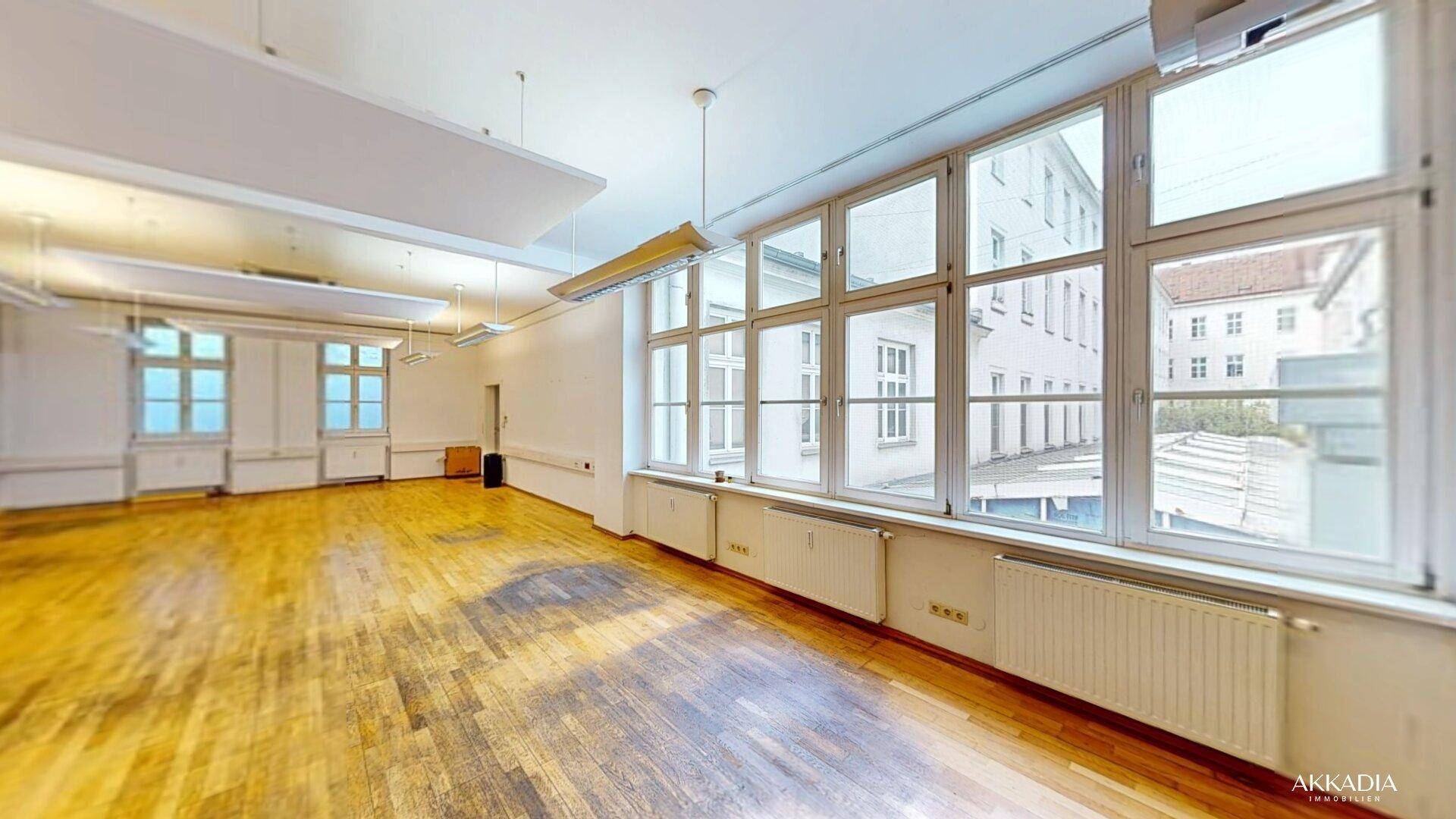Heller Büroraum mit großen Fenstern, die viel Tageslicht hereinlassen und einen Blick nach draußen bieten.