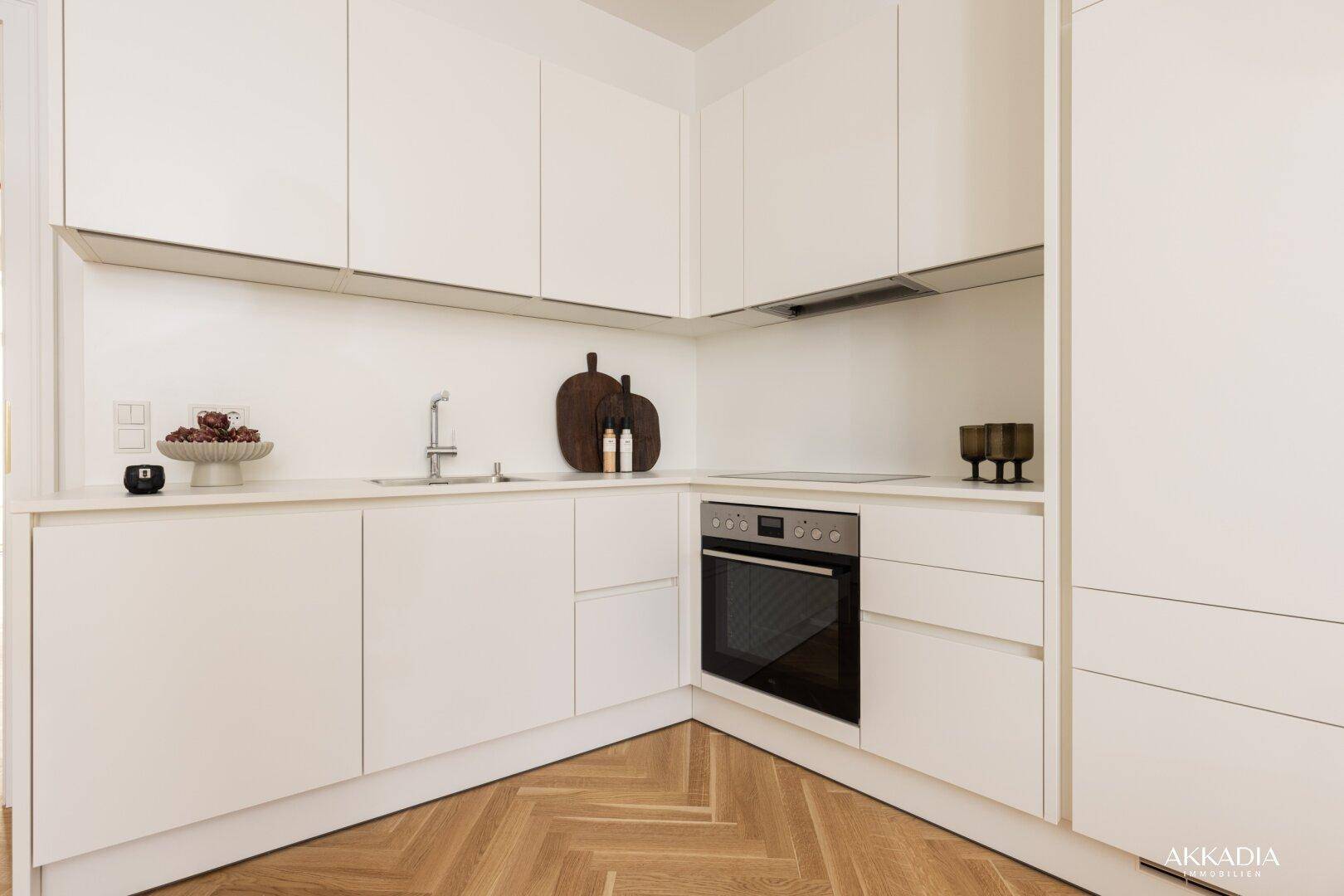 Detailansicht der modernen weißen Küche mit integriertem Backofen und Spülbecken.