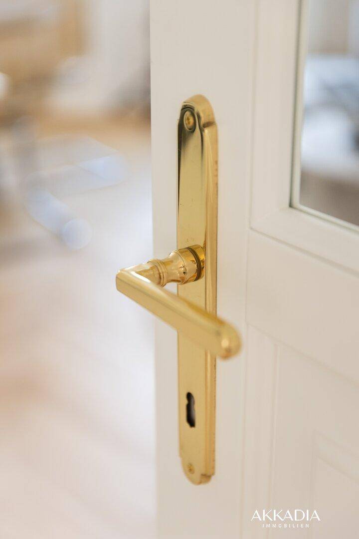Nahaufnahme einer eleganten goldenen Türfalle an einer weißen Innentür.