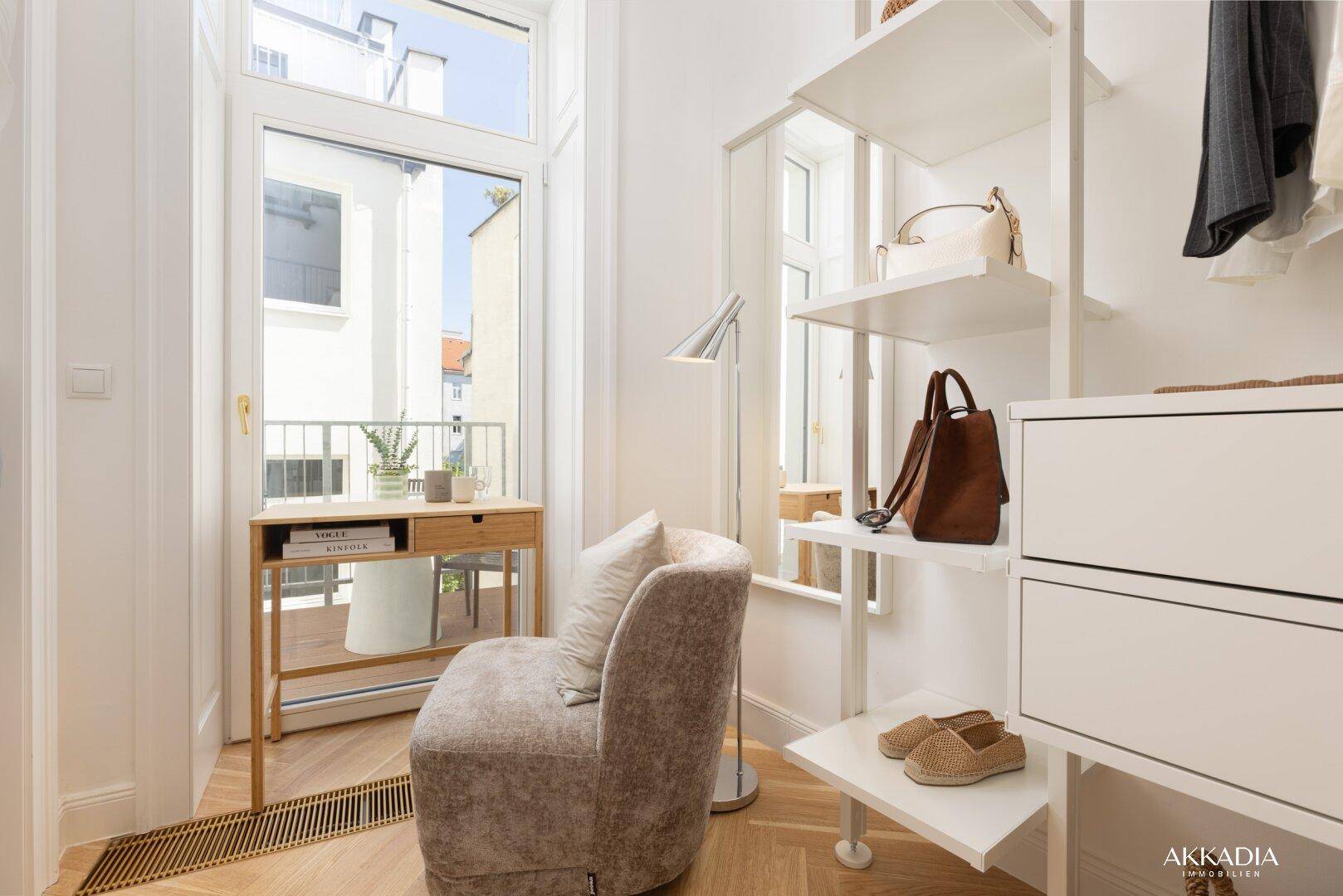 Schlafzimmerbereich mit Schreibtisch, Sessel und Zugang zu einem französischen Balkon.