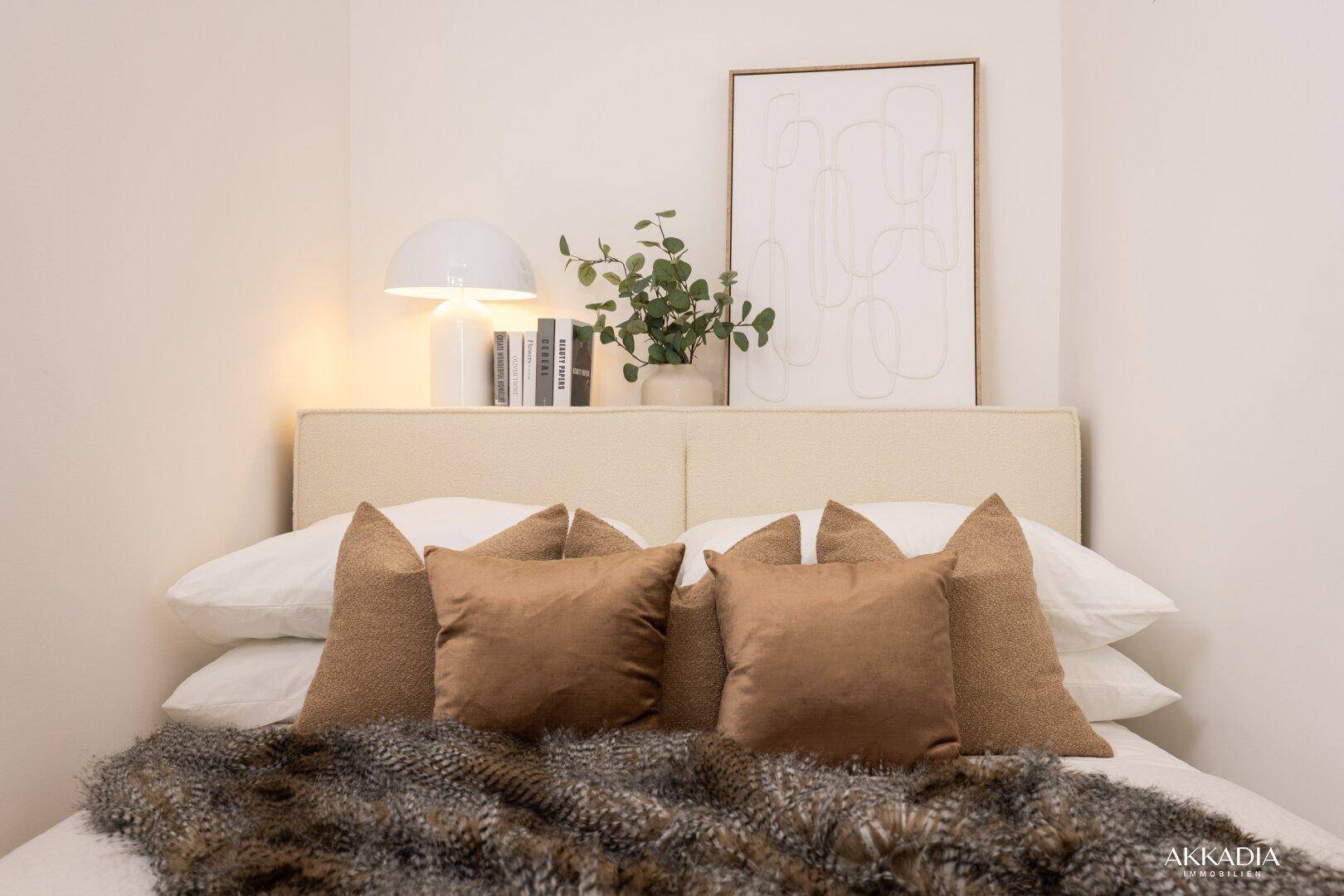 Gemütliches Doppelbett mit Kissen, Decke und Nachttischlampe im Schlafzimmer.