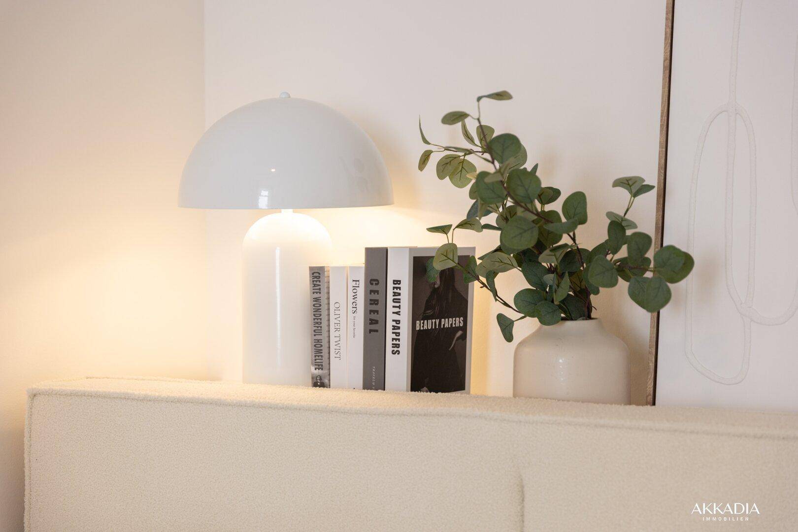 Detailansicht des Nachttisches mit moderner Lampe, Büchern und einer Grünpflanze.