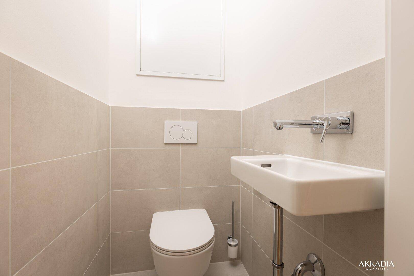 Modernes Gäste-WC mit wandhängendem WC und kleinem Handwaschbecken.