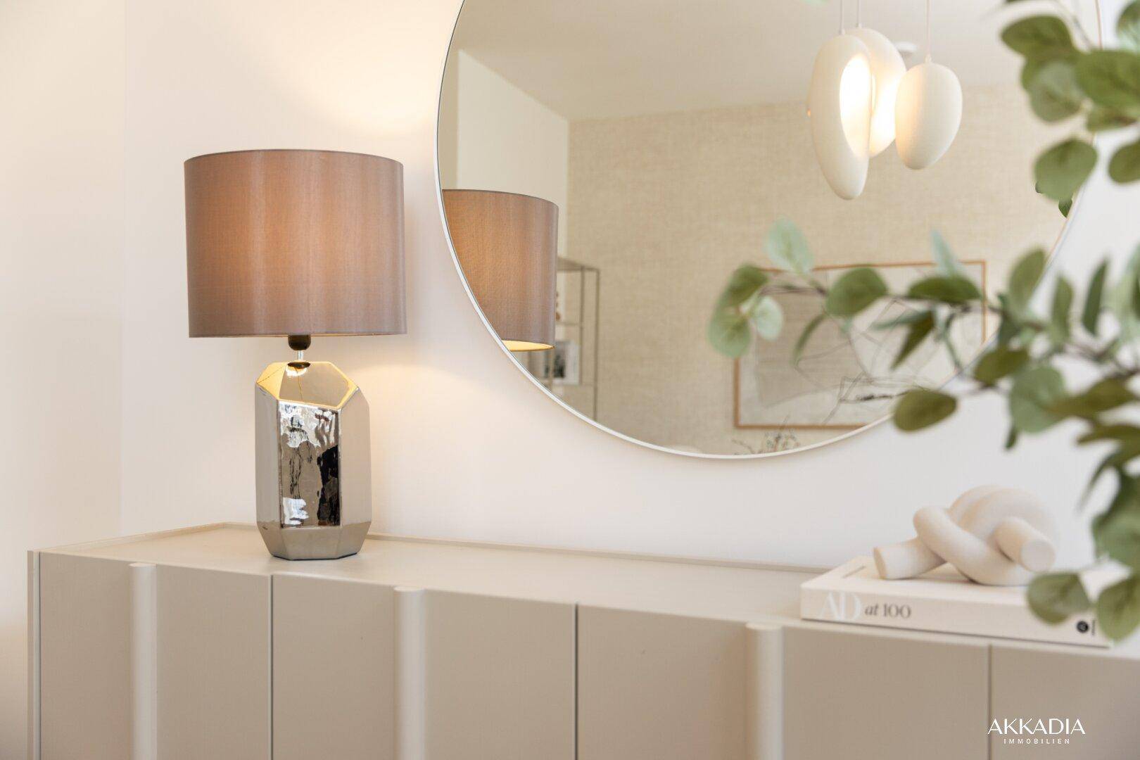 Moderner Konsolentisch mit Lampe und rundem Spiegel in einem hellen Eingangsbereich.