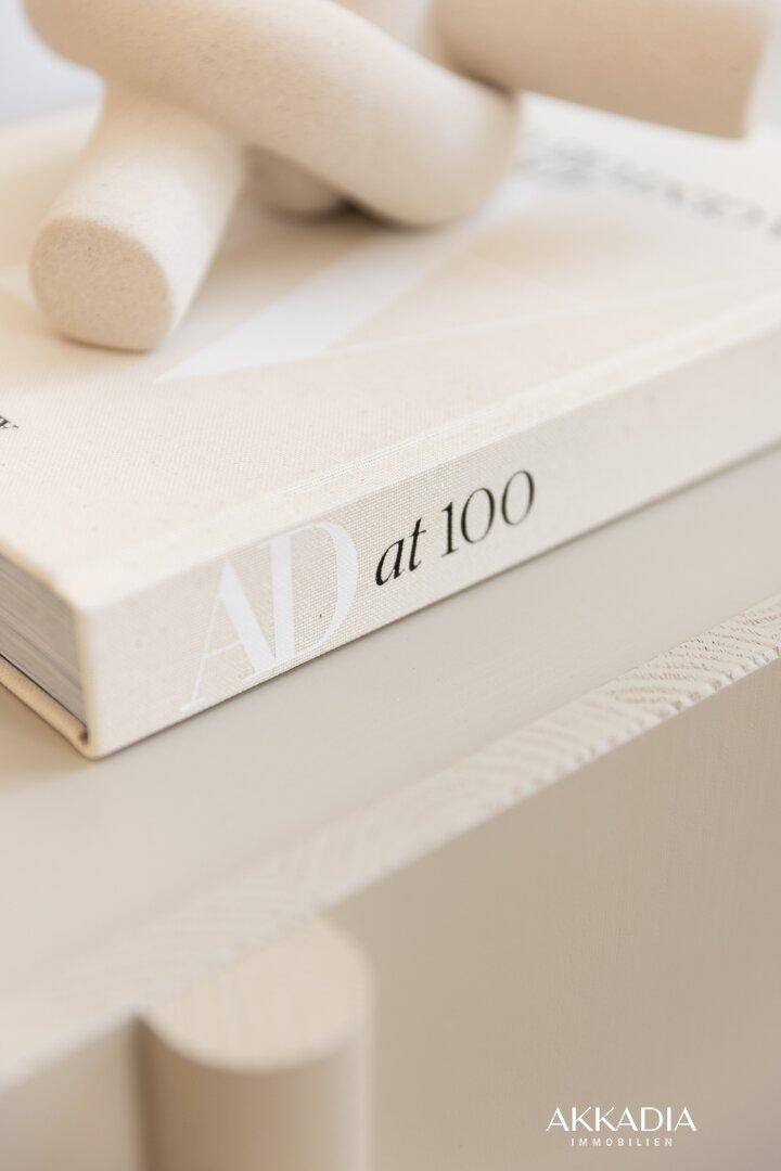 Nahaufnahme eines Buches "AD at 100" auf einem modernen, hellen Konsolentisch.