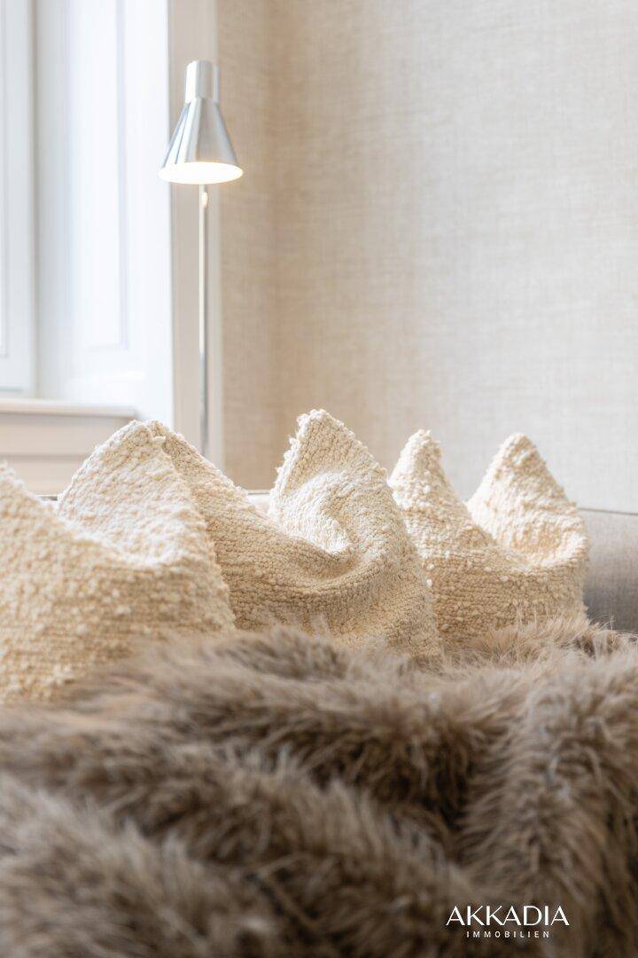 Gemütliche Kissen und eine weiche Decke auf einem Sofa, die eine einladende Atmosphäre schaffen.
