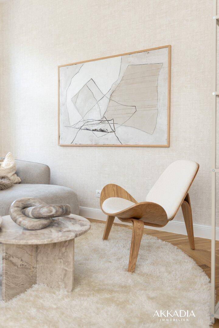 Heller Wohnbereich mit modernem Sofa, Couchtisch aus Stein und einem Designer-Sessel.