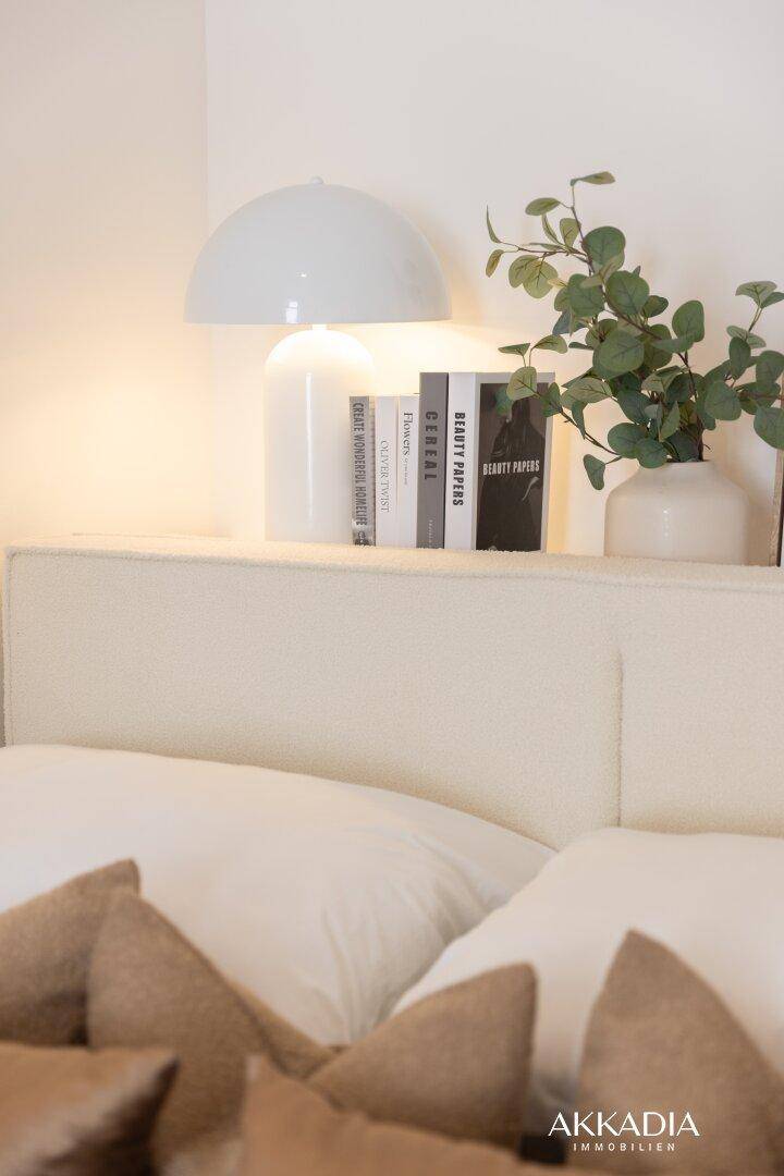 Nachttisch mit einer modernen Lampe, Büchern und einer grünen Pflanze, die Gemütlichkeit ausstrahlen.