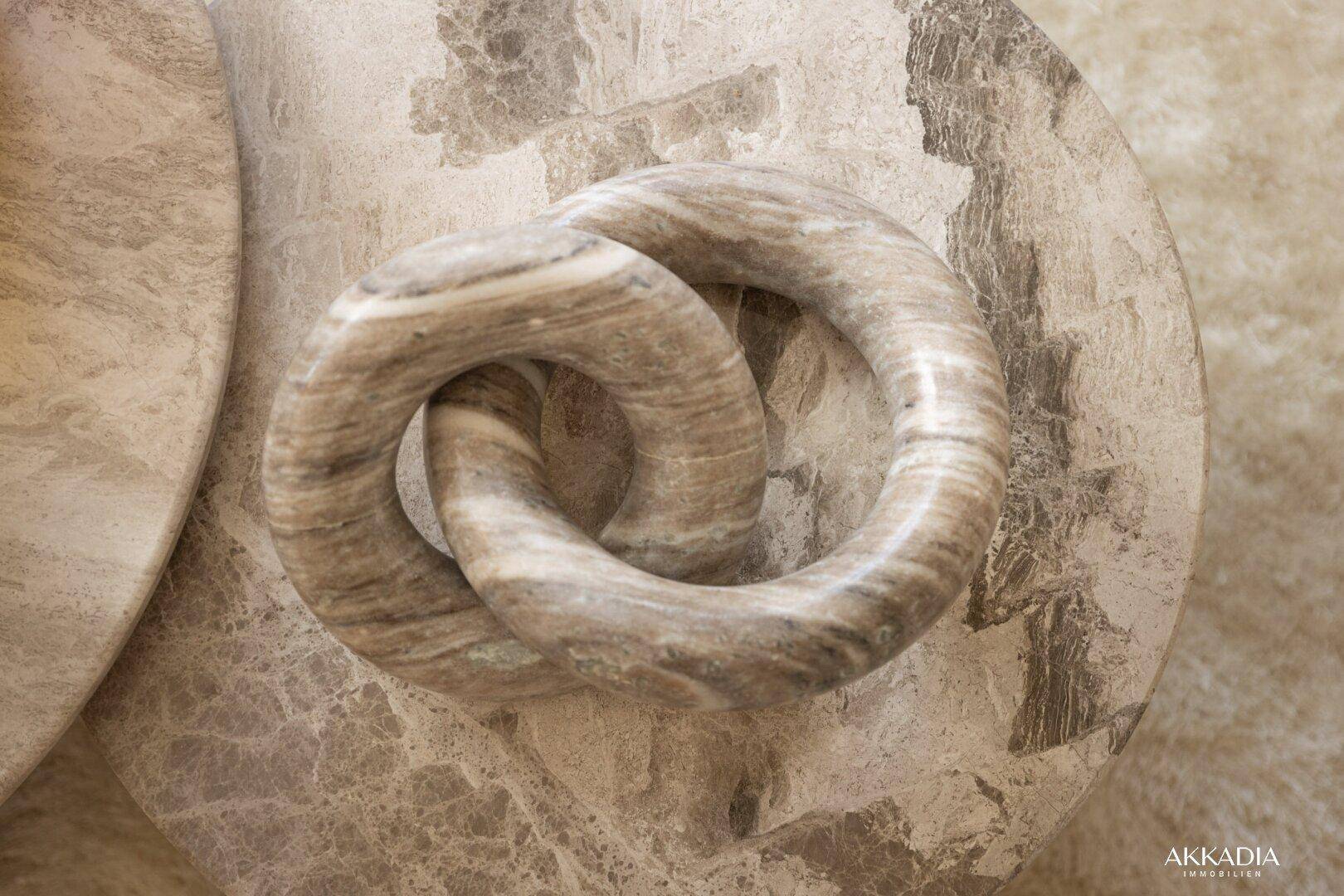 Detailaufnahme einer dekorativen Marmorskulptur in Knotenform auf einem Marmor-Couchtisch.