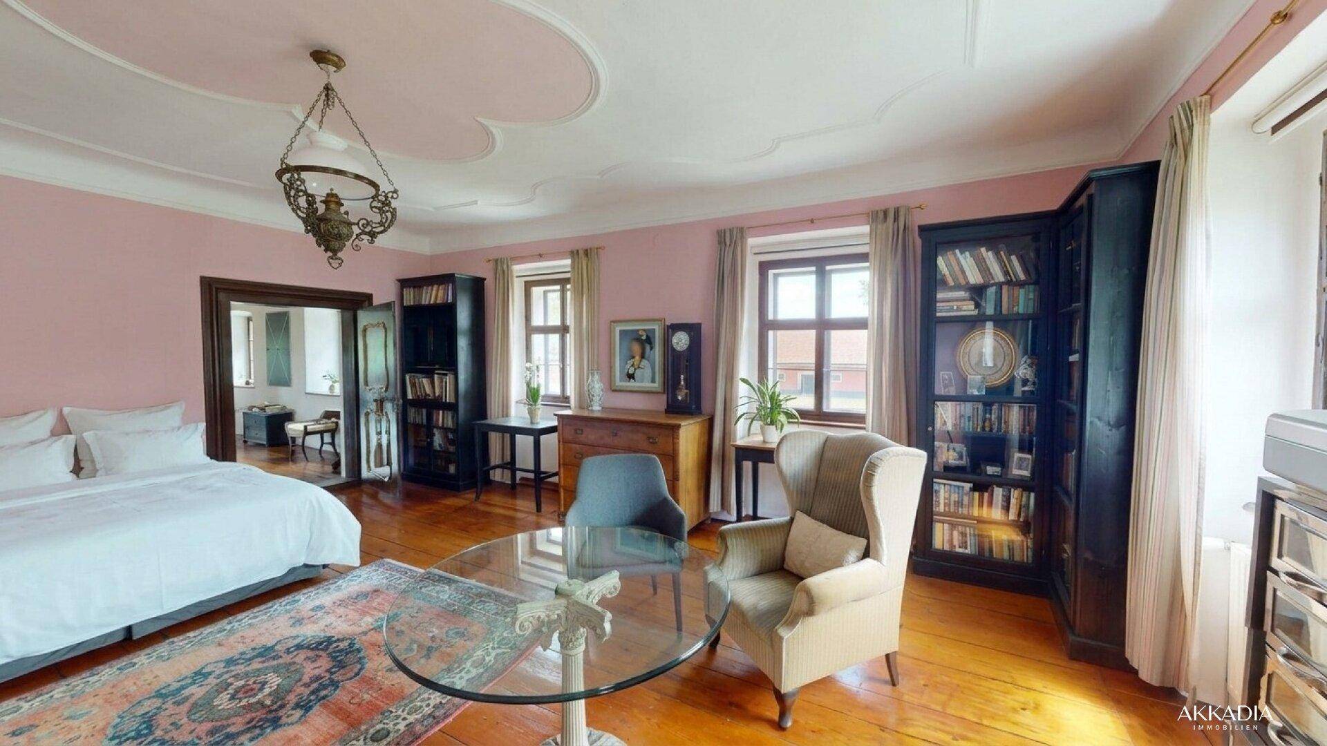 Großes Schlafzimmer mit rosa Wänden, Holzboden, Stuckdecke und antiken Möbeln.