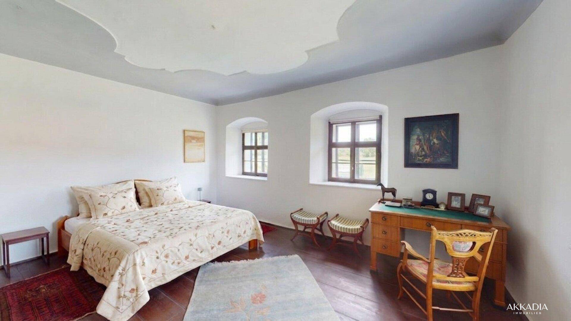 Elegantes Schlafzimmer mit Holzboden, weißer Stuckdecke und antiken Möbeln.