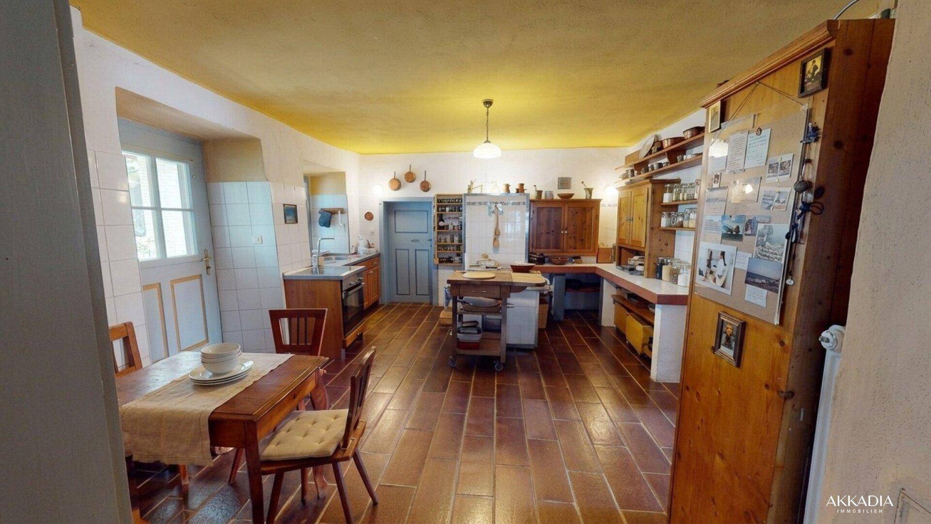 Geräumige traditionelle Küche mit Essbereich, Terrakottaboden und gelber Decke.
