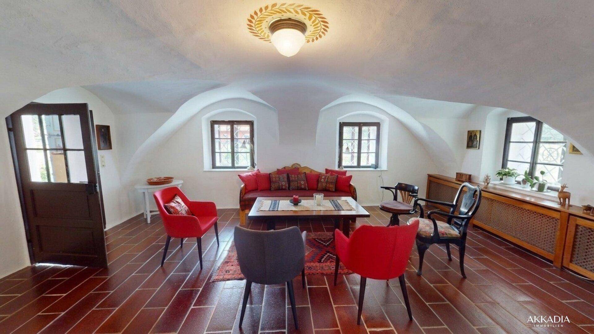 Gemütliches Wohnzimmer mit Gewölbedecke, Terrakottaboden und farbenfroher Einrichtung.