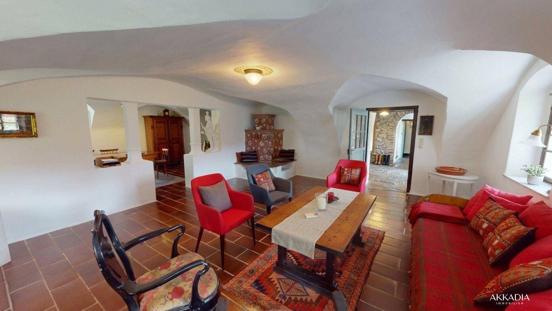 Geräumiges Wohnzimmer mit Gewölbedecke, Terrakottaboden und farbenfrohen Möbeln.