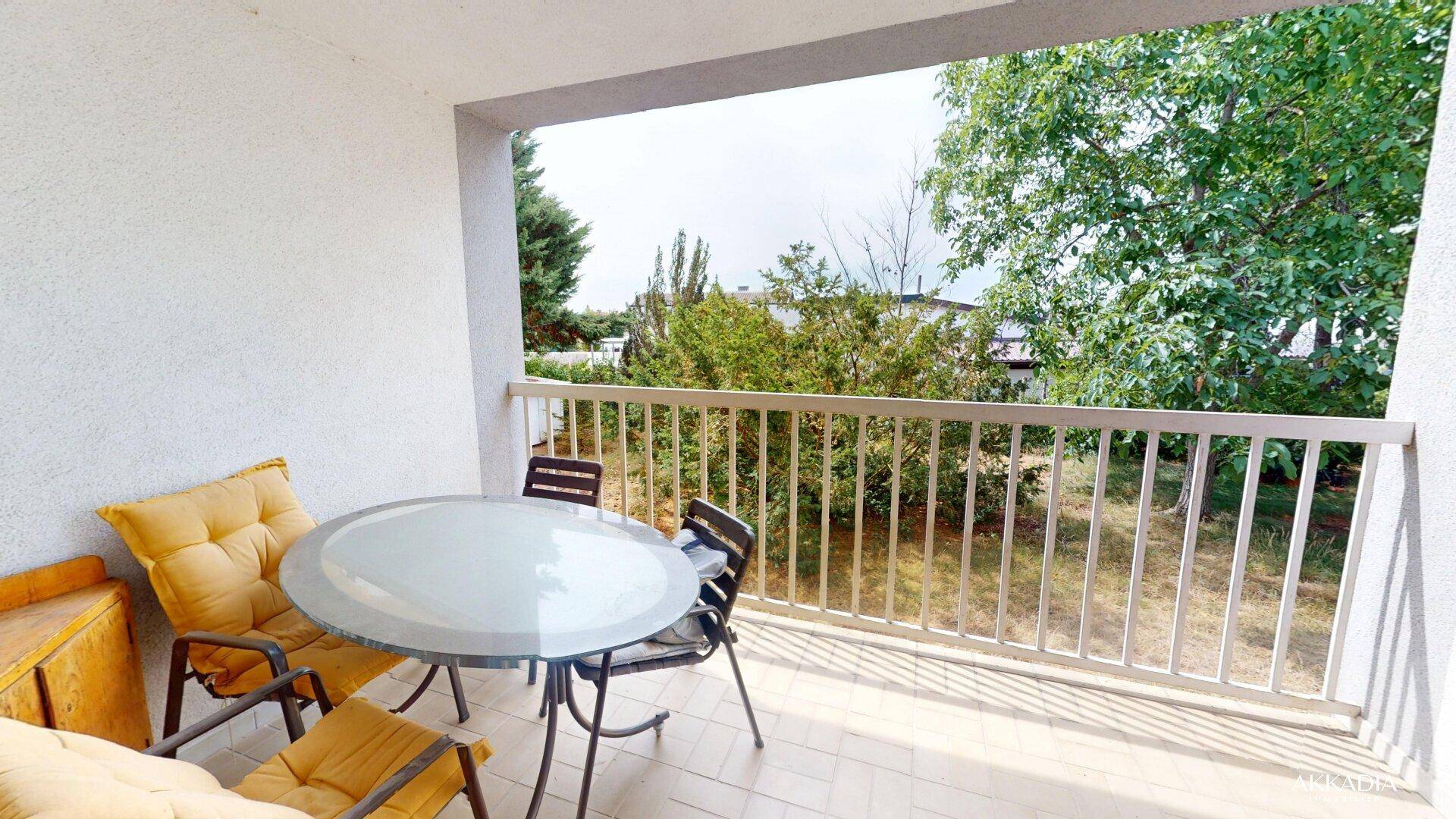 Heller Balkon mit Outdoor-Sitzgelegenheiten und einem angenehmen Blick ins Grüne.