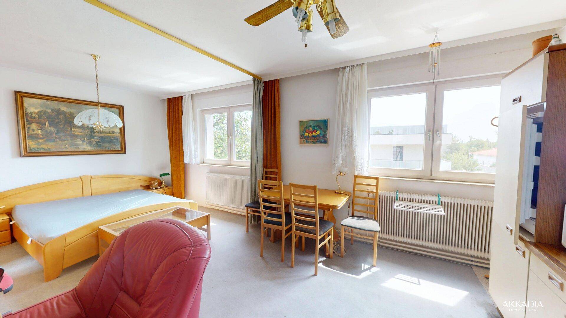 Kombinierter Wohn- und Schlafbereich mit Bett, Esstisch und einer kleinen Küchenzeile.