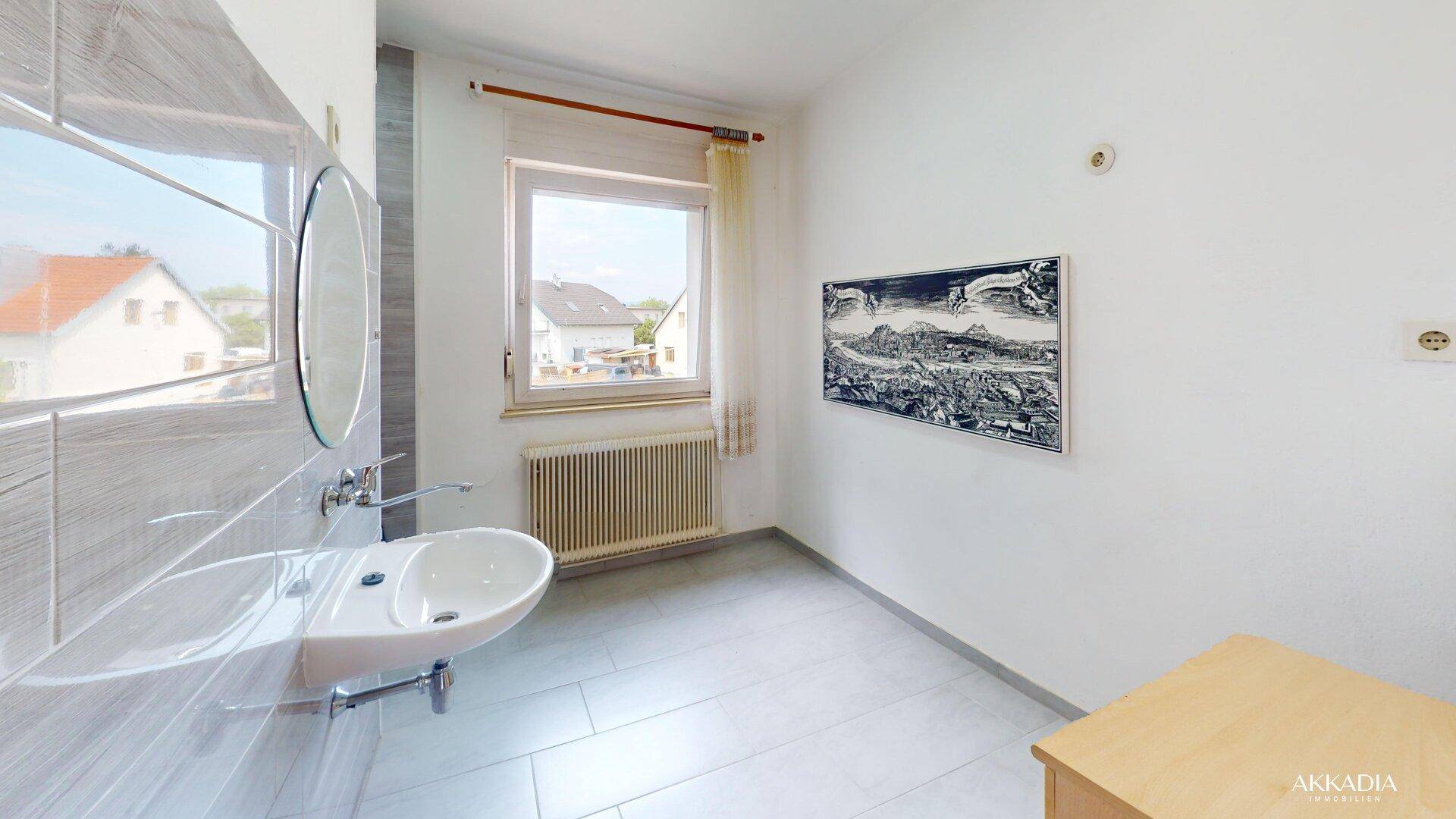 Helles Badezimmer mit Einzelwaschbecken, Spiegel und einem Fenster, bereit zur individuellen Gestaltung.