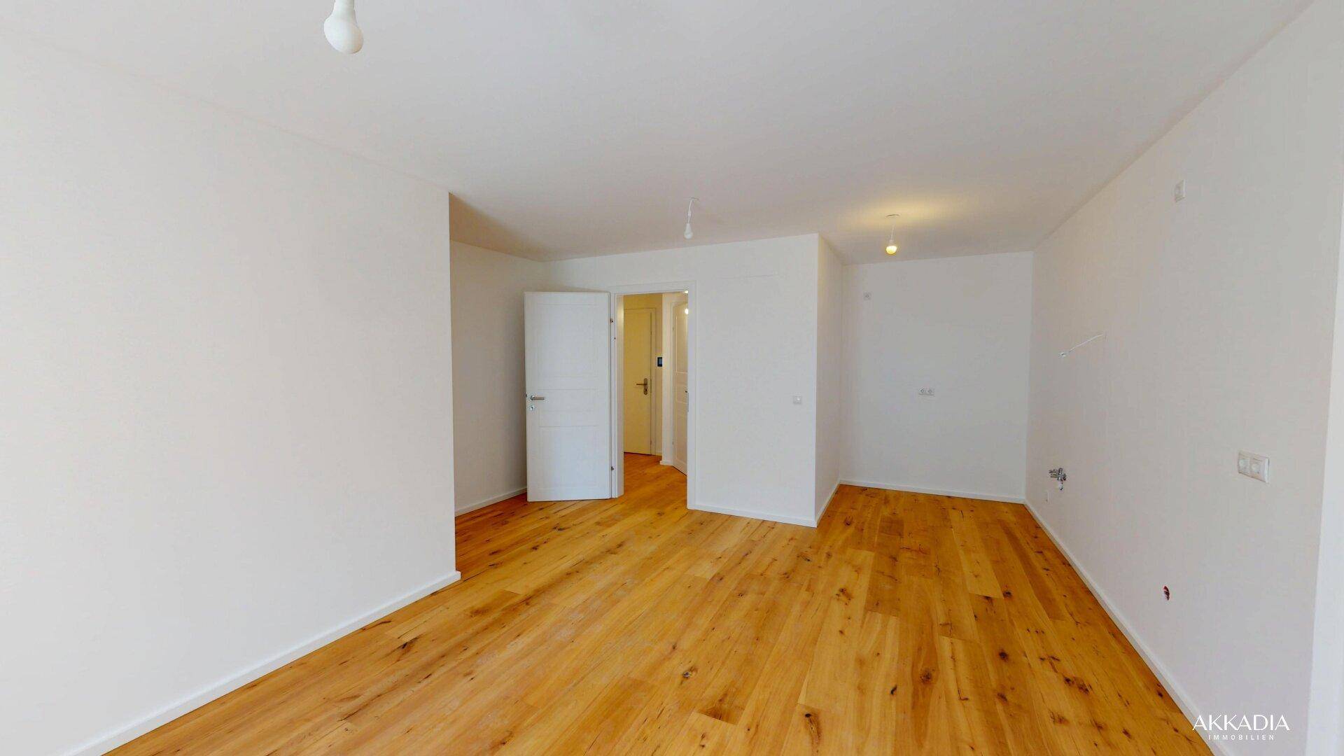 Geräumiger, heller Raum mit Holzboden und offener Tür zu einem angrenzenden Bereich.