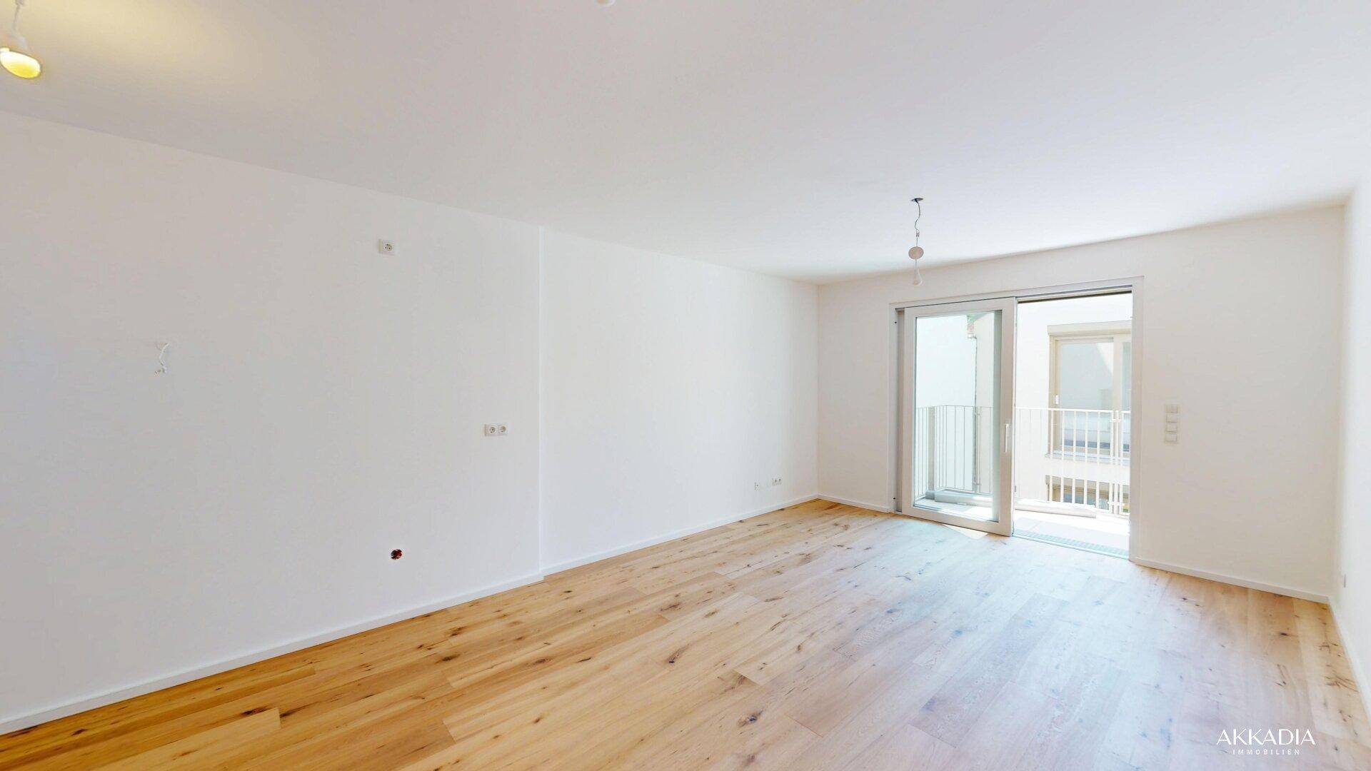 Heller Wohnraum mit Holzboden und großer Glasschiebetür, die viel Tageslicht hereinlässt.